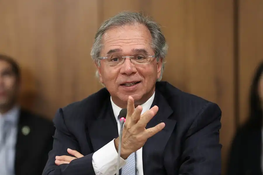 Homem de terno e óculos falando ao microfone em uma reunião, imagem ilustrativa do artigo sobre o inquérito da Polícia Federal envolvendo a OnilX